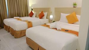 três camas num quarto de hotel com almofadas brancas e laranja em bintang hotel em Kuala Lumpur