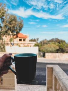 una mano sosteniendo una taza de café negra en un balcón en Pembroke Parkside Maisonette, en Pembroke