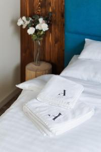 two white towels on a bed with a vase of flowers at Avenue Chalet in Špindlerův Mlýn