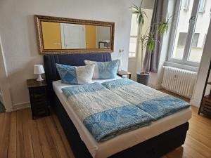 a bedroom with a bed with a blue comforter and a mirror at Residence am Rathausplatz 3 in Saarbrücken