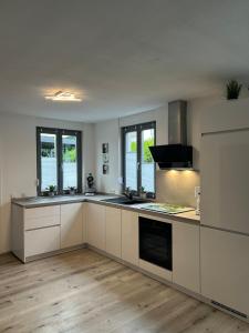 eine große Küche mit weißen Schränken und Fenstern in der Unterkunft Ferienwohnung Trunk in Roschbach
