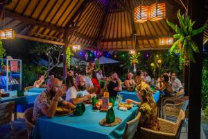 un groupe de personnes assises à table dans un restaurant dans l'établissement Sunset Garden Nusa Lembongan, à Nusa Lembongan