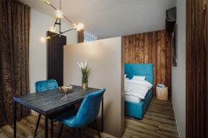 a dining room with a table and blue chairs and a bed at Avenue Chalet in Špindlerův Mlýn