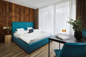 a bedroom with a blue bed and a table at Avenue Chalet in Špindlerův Mlýn