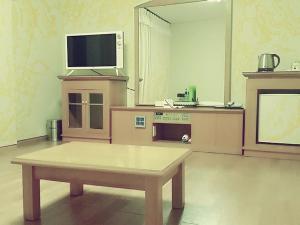 uma sala de estar com uma mesa e uma televisão em Daedong Hotel em Jeju