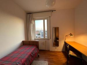 a bedroom with a bed and a desk and a window at CASABELLA in Monza