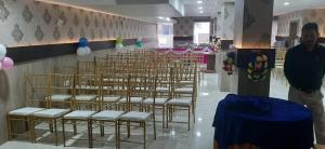un homme debout devant une pièce avec des chaises dans l'établissement Hotel Paramveer, à Muzaffarpur