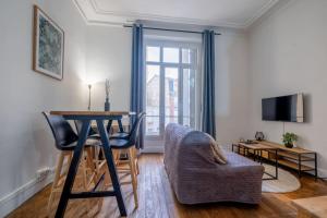 a living room with a table and a chair at Le Brillant - Studio in Reims