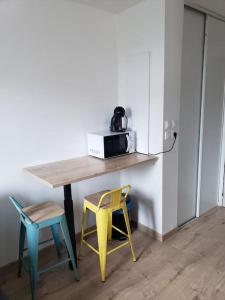a table with two chairs and a microwave on it at Charmant studio à 2 pas du tram in Nantes