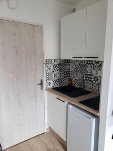 a kitchen with a white cabinet and a refrigerator at Charmant studio à 2 pas du tram in Nantes