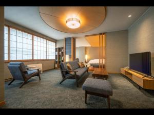 una camera d'albergo con zona soggiorno e TV di Dai Onsen Matsudaya Ryokan a Hanamaki