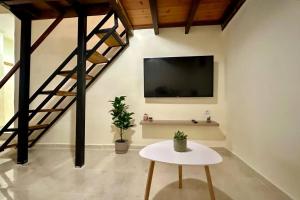 a living room with a table and a tv on a wall at The Nook in Maleme