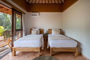 two beds in a room with a balcony at The Kayuan Lumbur Resort Ubud in Ubud