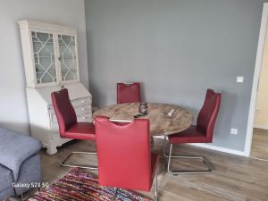 a dining room with a table and four red chairs at Wohnung Adam in Kelkheim