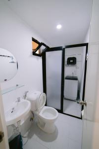 a white bathroom with a toilet and a sink at Royal Oceancrest Mactan Condominium Unit 1418 in Sudtungan
