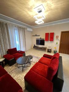 - un salon avec des canapés rouges et une télévision dans l'établissement SkyBase, à Tirana