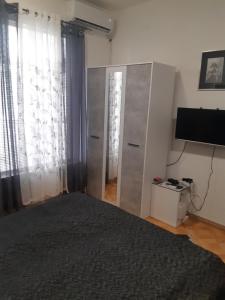 um quarto com uma cama, uma televisão e cortinas em Apartman STEVAN Vrnjačka Banja em Vrnjačka Banja