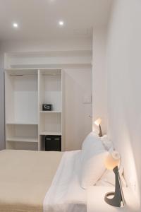 una camera bianca con un letto e una lampada di Posterla22 Ensuite Rooms a Bologna Altre 11 foto