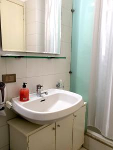 - un lavabo dans la salle de bains avec une bouteille de savon rouge dans l'établissement Residence le Dune, à Lido di Camaiore