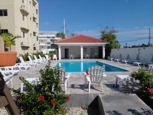 a swimming pool with chairs and a building at Caleta in La Romana