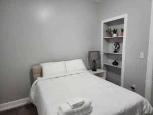 Un dormitorio con una cama blanca con toallas. en Fortune Suits and Apartment en Albany