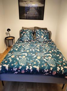 a bed with a blue comforter with flowers on it at Rien que pour vous in Reichstett