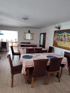 una sala da pranzo con tavoli, sedie e un dipinto di Pensiunea Piatra Mandrutului a Scărişoara