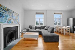 a living room with a couch and a fireplace at Queen’s Park, Spacious 3 Bedroom Flat in London