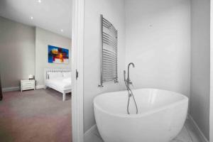 a white bath tub in a room with a bedroom at Queen’s Park, Spacious 3 Bedroom Flat in London