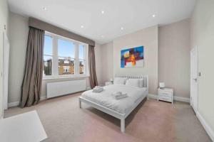 a white bedroom with a bed and a window at Queen’s Park, Spacious 3 Bedroom Flat in London