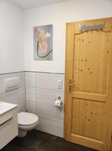 a bathroom with a toilet and a wooden door at Ferienwohnung Katrin Spindler in Ilmenau