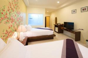 a hotel room with two beds and a television at Maryo Resort - SHA Plus in Chiang Rai
