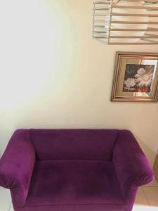 un sofá púrpura en una sala de estar con una foto en JT Tagaytay Suites en Tagaytay
