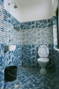 TAJ HERITAGE Hotel And Restaurant -call 94353-5O876 في جورهات: حمام من البلاط الأزرق مع مرحاض ومغسلة