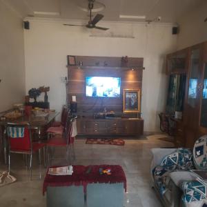 uma sala de estar com uma televisão grande e uma mesa em Premanand's House em Raipur