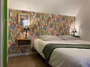 Dormitorio con cama y papel pintado colorido en Chambre d'hôtes sur le chemin de la Loire à vélo en Les Ponts-de-Cé