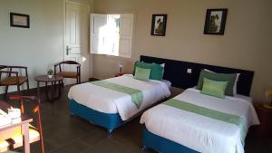 a bedroom with two beds and a table and chairs at Koh Ker Hotel and Restaurant in Phumĭ Mréch