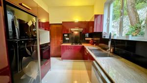 een keuken met rode kasten en een zwarte koelkast bij Villa De Lanerolle in Attidiya