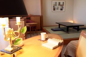 une chambre avec une table, une lampe et un livre dans l'établissement Satoyama Auberge & Hot Spring Wellness Spa Sakuragaike Kurgarden, à Nanto