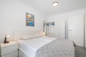 a white bedroom with a bed and a mirror at Infinity Dalmatia Apartments in Vinjerac