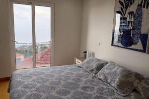 um quarto com uma cama e uma grande janela em Casa Monte Ponta do Sol SeaViews em Ponta do Sol