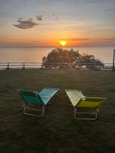 two chairs sitting on the grass with the sunset in the background at Pousada Olivas do Tapajós in Belterra