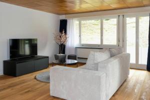 un soggiorno con divano bianco e TV di Mariposa Spiez a Spiez