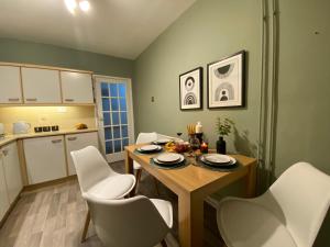 a kitchen with a wooden table and white chairs at Oadby Town Mid-Century Bungalow in Oadby