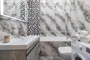 a bathroom with a sink and a washing machine at Стильные апартаменты in Astana +12 photos