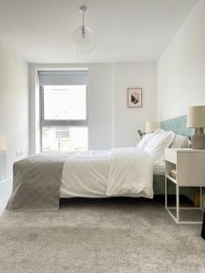a white bedroom with a large bed and a window at Central Shoreditch Flat By Box Park & Spitalfields Market in London