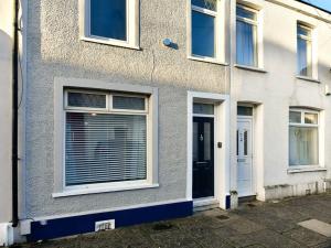 ein weißes Haus mit einer Tür und Fenstern in der Unterkunft Pass the Keys Cosy 2 bed home in Pontcanna in Cardiff