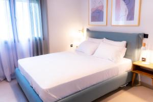 a bedroom with a bed with white sheets and a window at Mi casa su casa in Néa Koútali