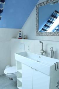 a white bathroom with a sink and a toilet at Haus Wildgans - Ferienwohnung Sonnenblume in Behrensdorf