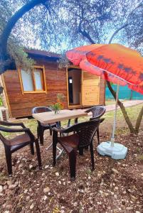 une table et des chaises avec un parasol et une cabine dans l'établissement Köklü Ahşap Tatil Evleri, à Antalya